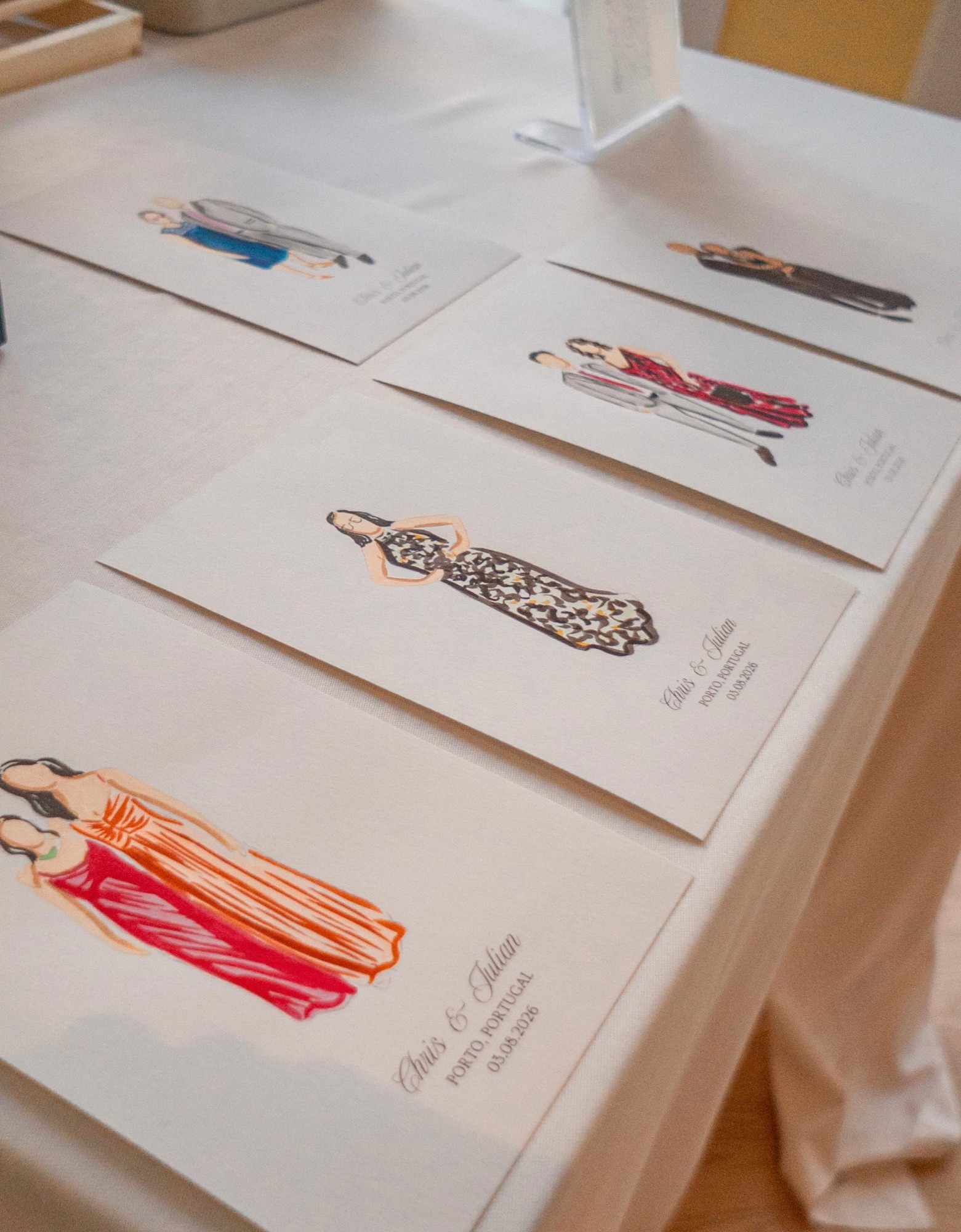 Finished portraits resting on the linen table, each signed with the couple's names · Souluarte
