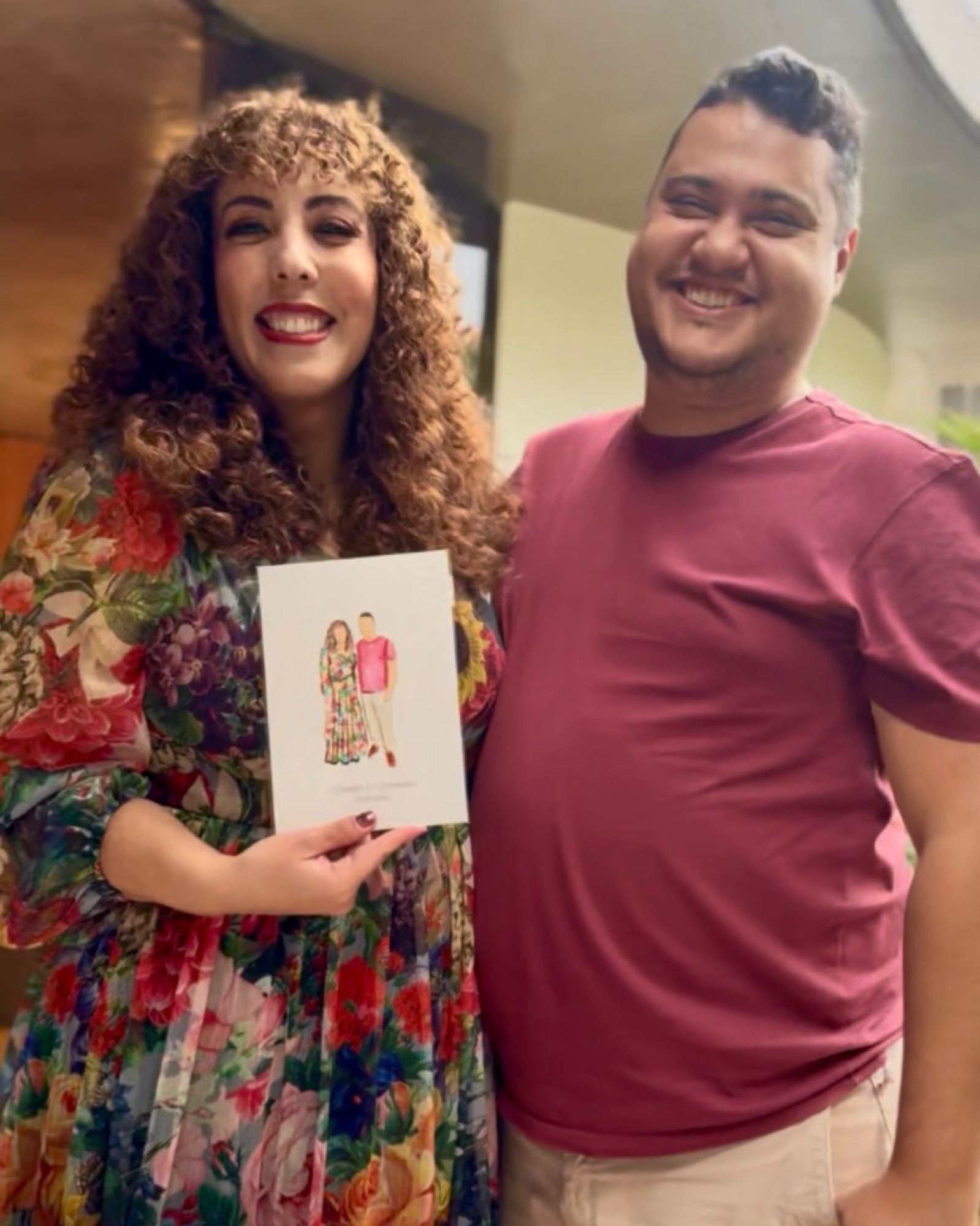 A couple smiling as they hold the live watercolour portrait painted for them · Souluarte