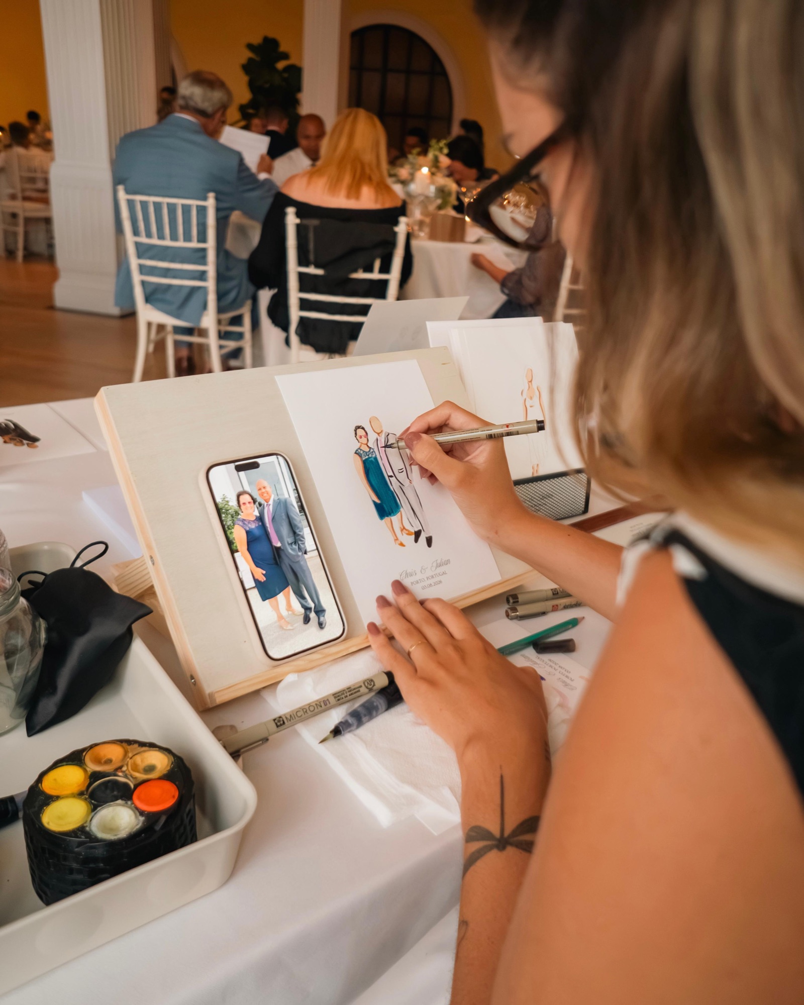 Close view of a guest portrait being drawn from a photo during the reception · Souluarte