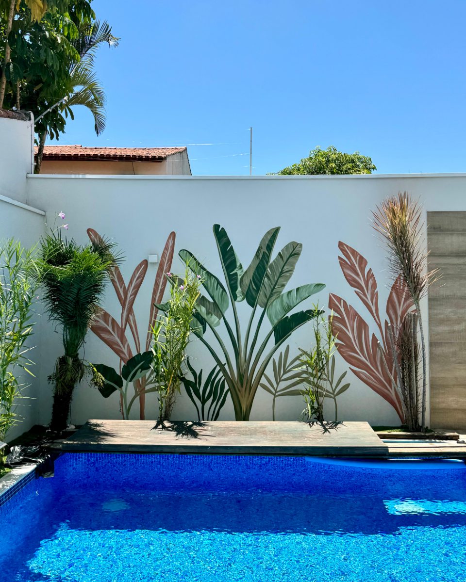 Poolside mural of banana leaves and traveller’s palms on a white wall · Souluarte