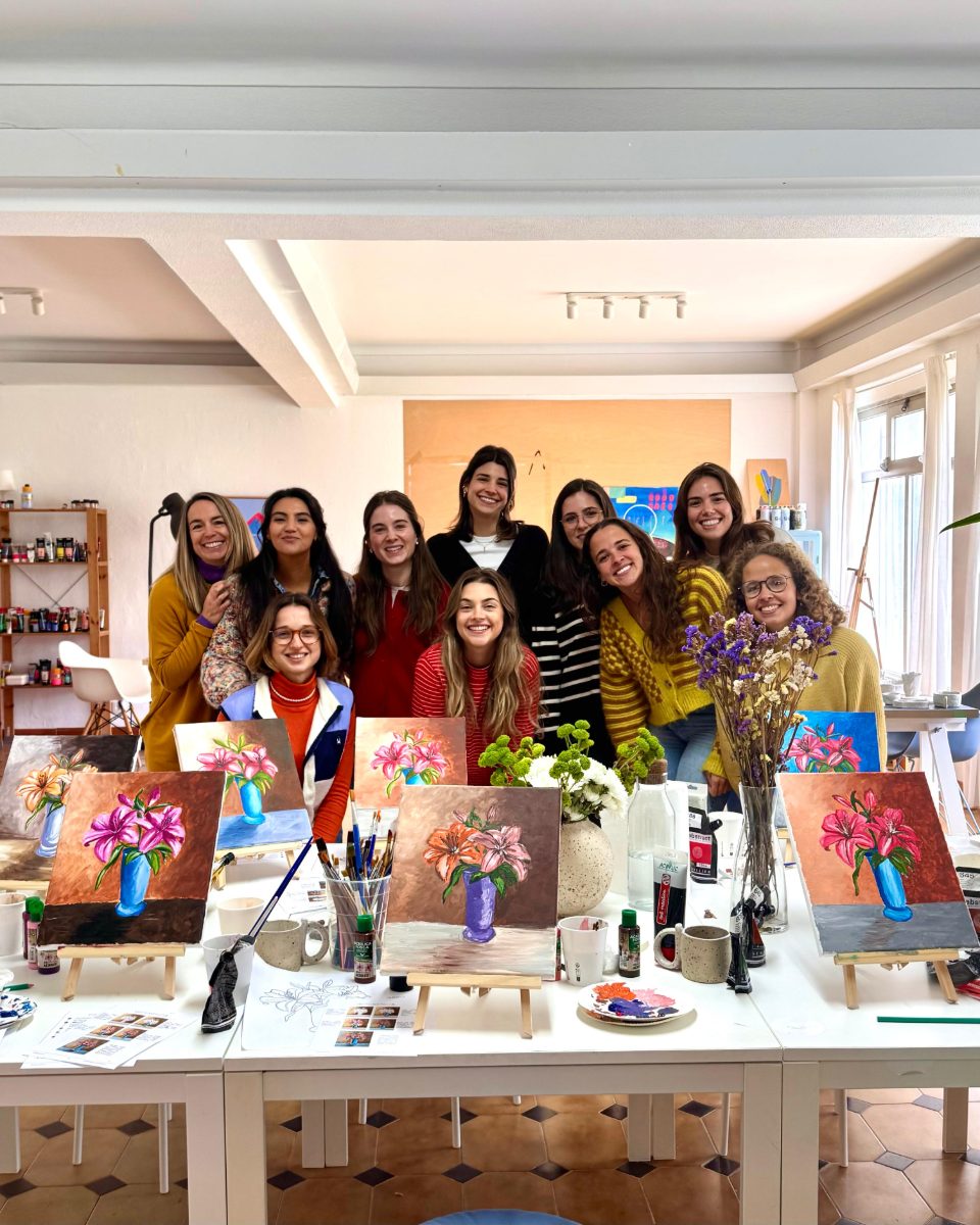Group of participants with their finished flower paintings in the bright studio · Souluarte