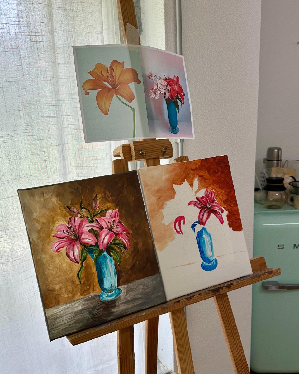 Two finished lily canvases drying on the easel by the window · Souluarte
