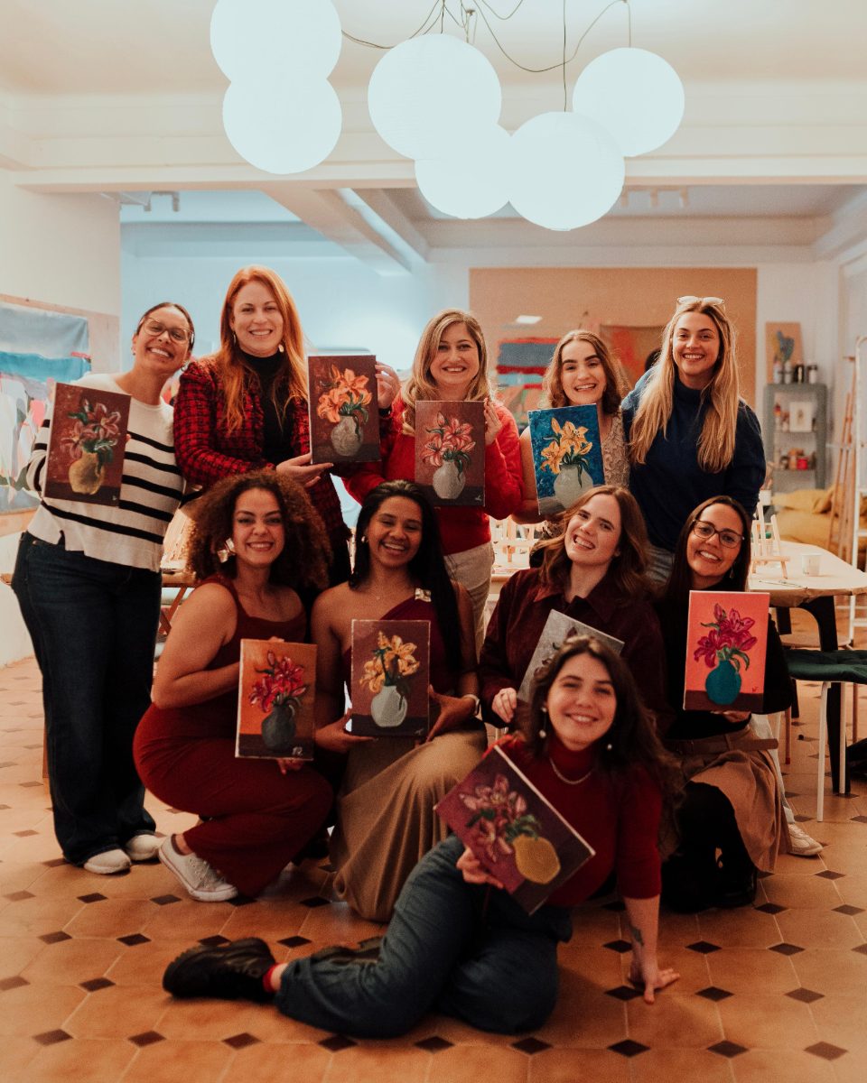 Group holding their finished lily paintings at the end of a workshop · Souluarte