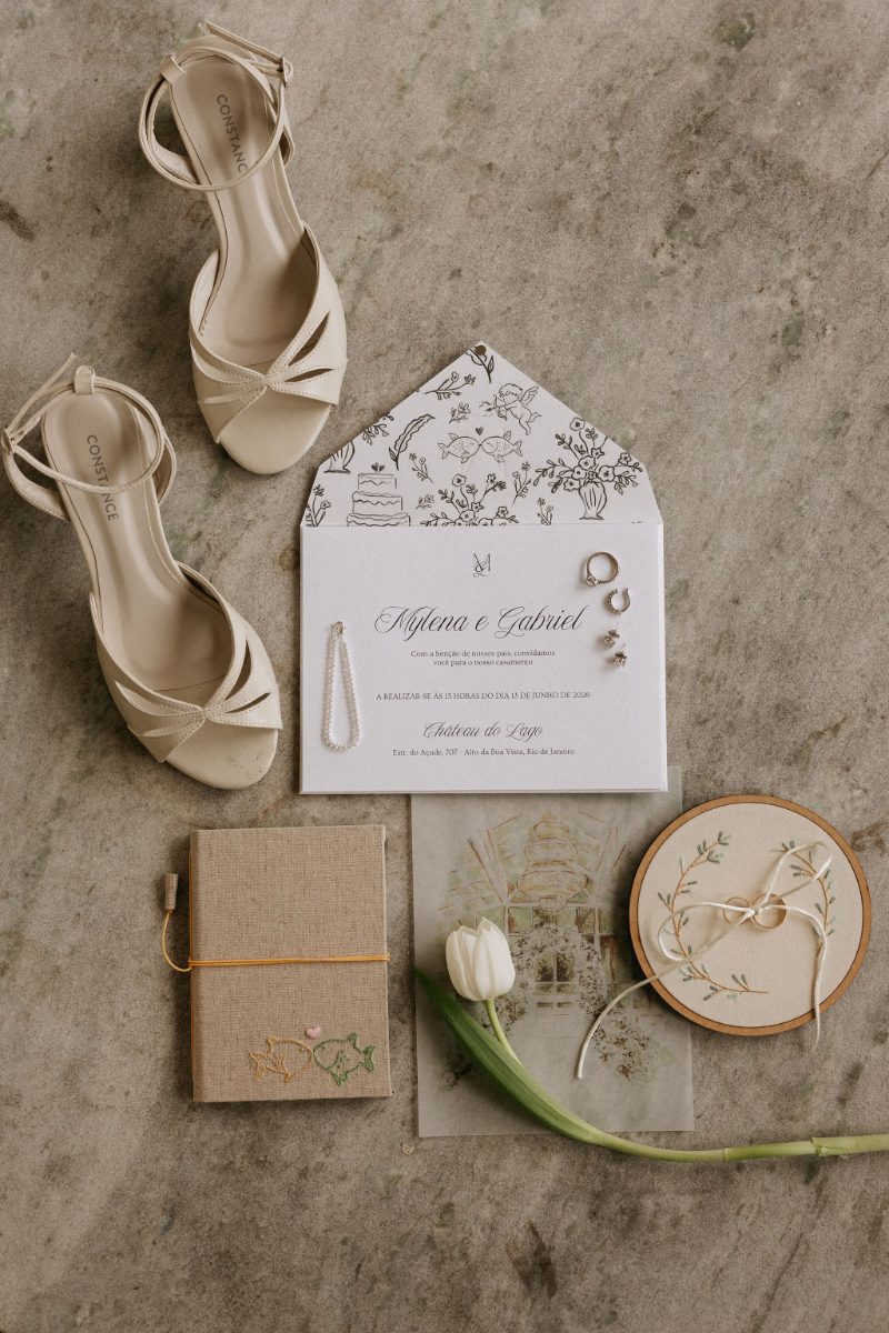 Invitation flat lay with shoes, rings and the illustrated envelope liner · Souluarte